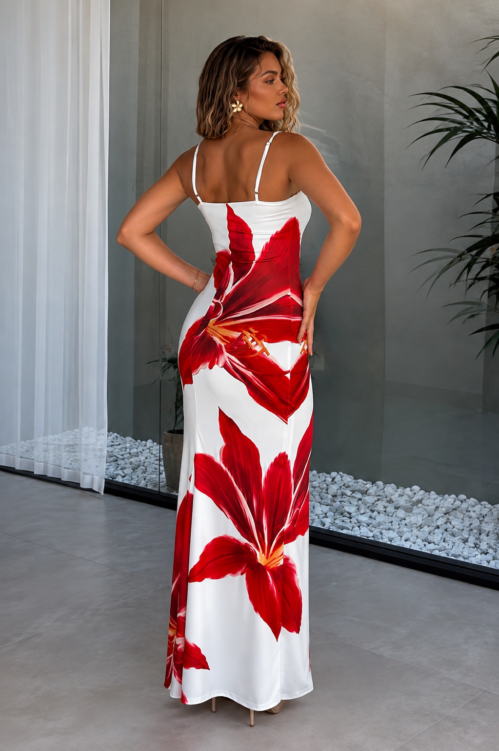 Woman wearing a white maxi dress with bold red floral print, back view