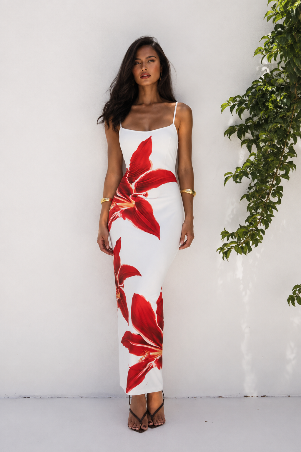 Woman wearing a white maxi dress with bold red floral print, front view